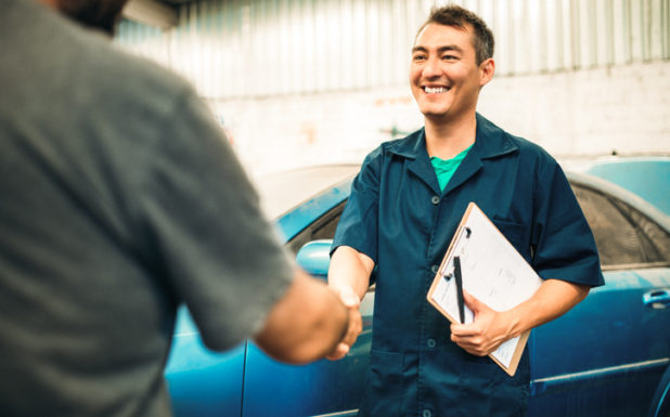 Smiling mechanic shaking hands with a person.