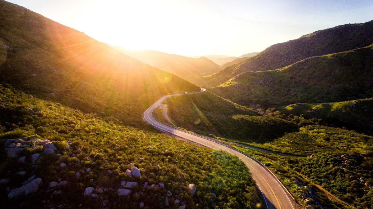 Photo of a road winding through sun-kissed hills.